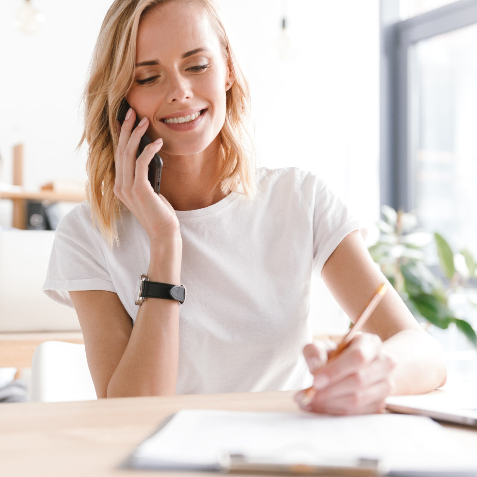 Smiling woman manager working with documents while sitting at the office with man co worker on a background